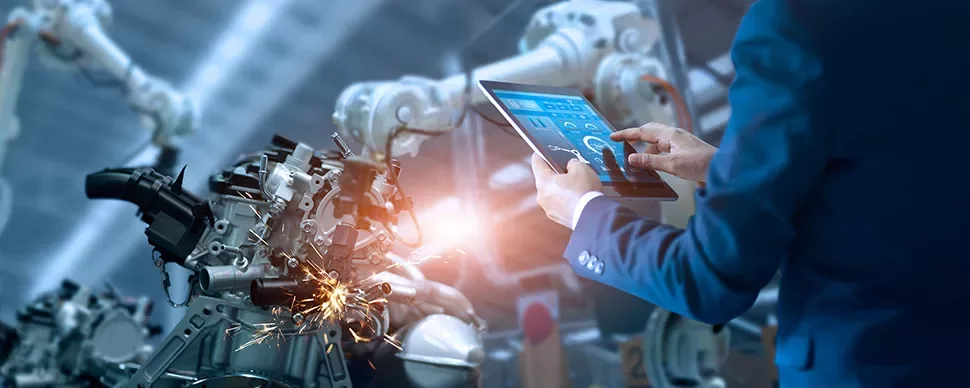 Personne utilisant une tablette pour contrôler un bras robotique en usine.