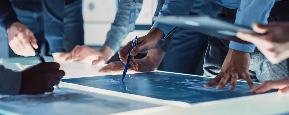 Personnes discutant autour d'une table avec des plans.