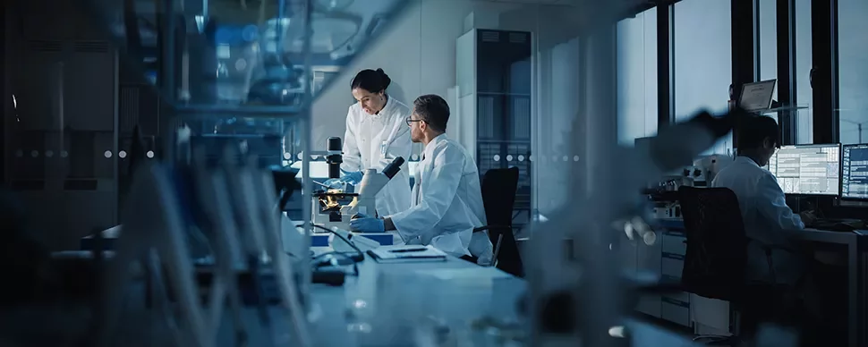 Scientifiques en laboratoire examinant un échantillon sous microscope.