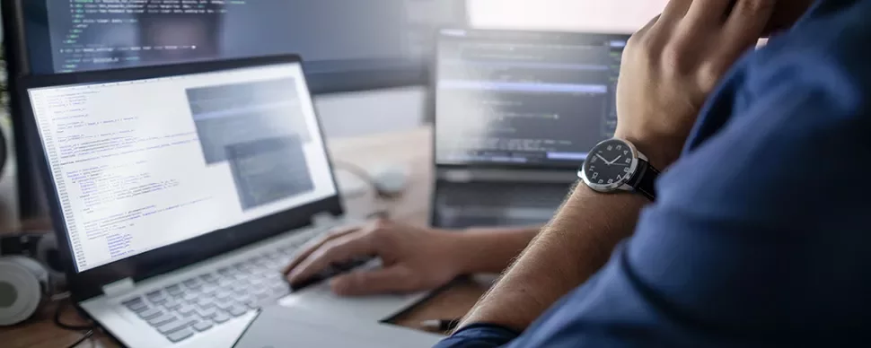 Personne utilisant un ordinateur portable avec du code à l'écran.