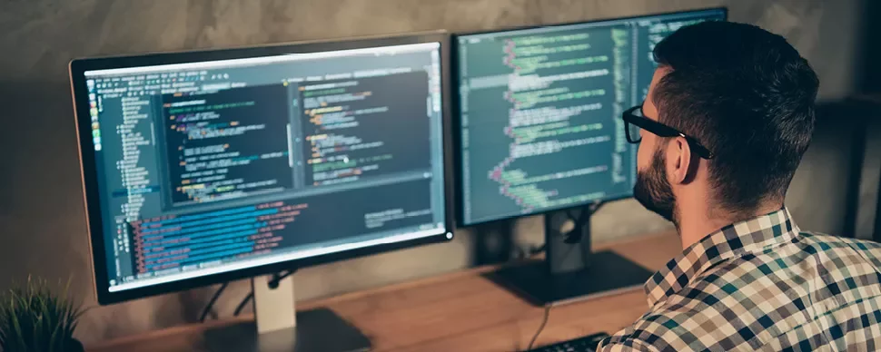 Personne travaillant sur deux écrans d'ordinateur avec du code.