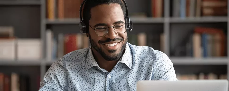 Personne souriante avec casque, utilisant un laptop.