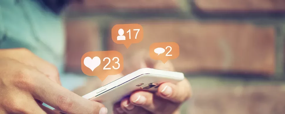 Personne tenant un téléphone avec des icônes de médias sociaux.