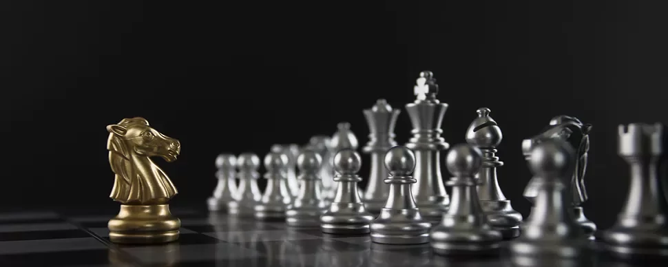 Pièce d'échecs dorée face à un rang de pièces argentées.