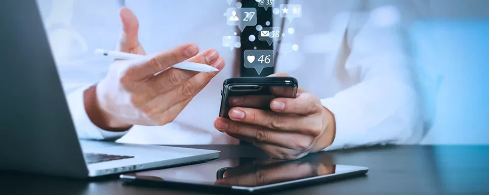 Personne utilisant un smartphone avec des icônes de médias sociaux flottantes.