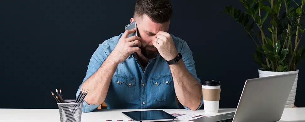 Personne au bureau avec téléphone, lunettes et ordinateur.