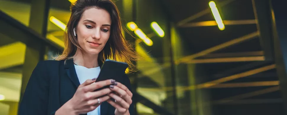 Personne utilisant un smartphone à l'extérieur, écouteurs sans fil.