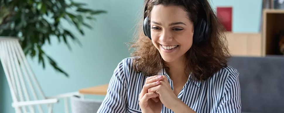 Personne souriante avec des écouteurs, travaillant en ligne.