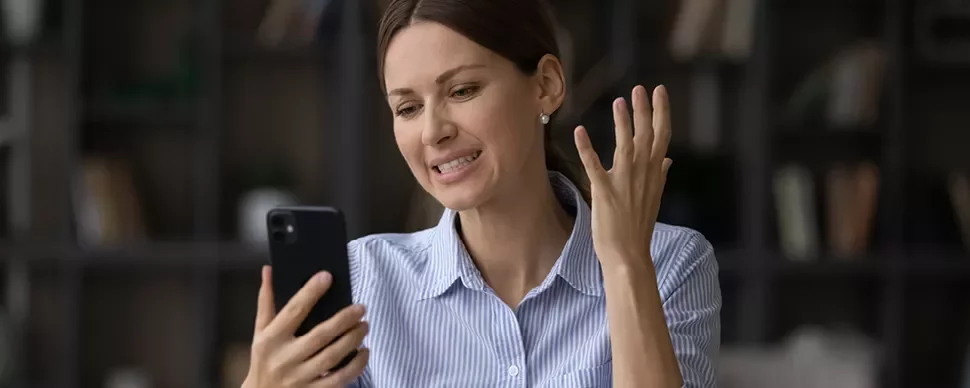 Personne regardant un téléphone avec une expression de frustration.