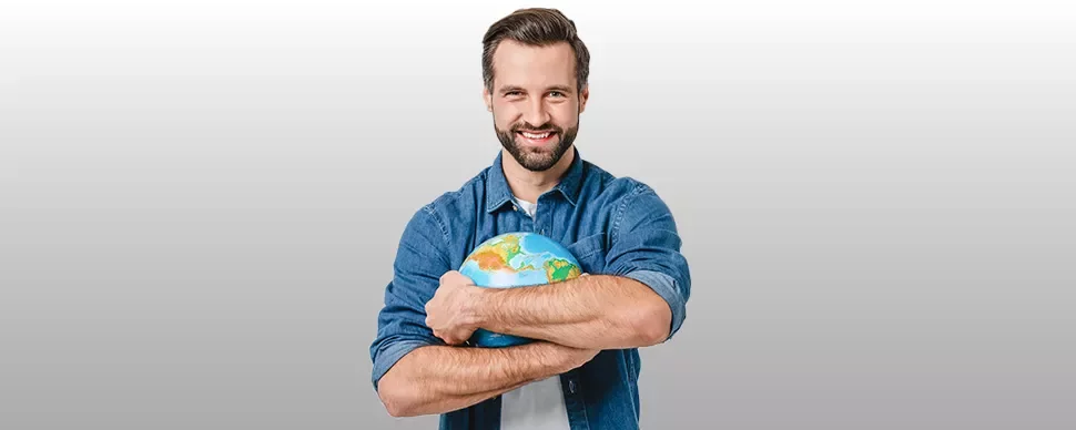 Personne tenant un globe terrestre avec un sourire.
