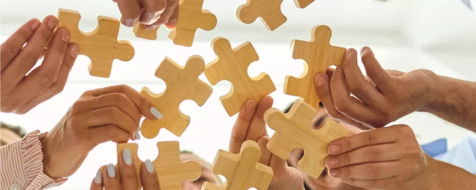 Des personnes tenant des pièces de puzzle en bois.
