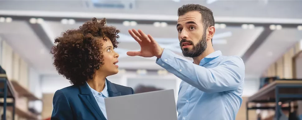 Deux personnes en discussion dans un bureau moderne.