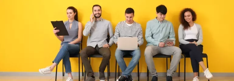 Groupe de personnes assises contre un mur jaune.