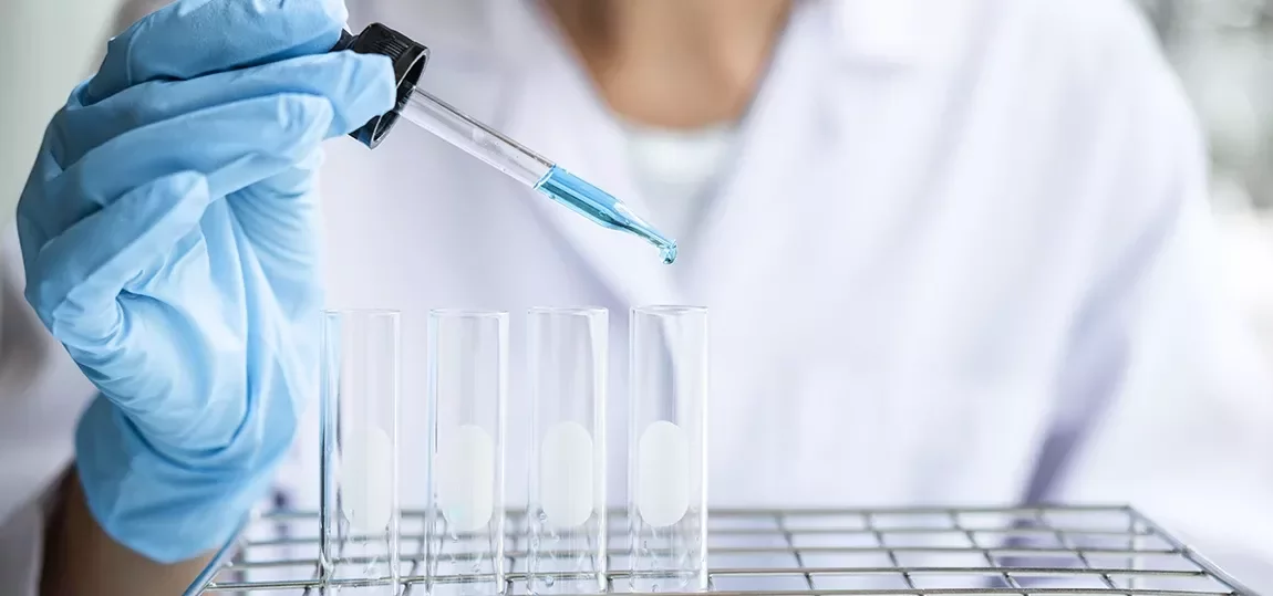 Professionnel maniant une pipette au dessus de tubes à essais
