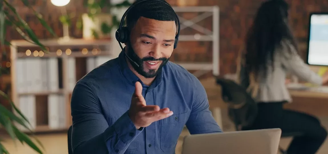 Homme souriant au téléphone devant son ordinateur