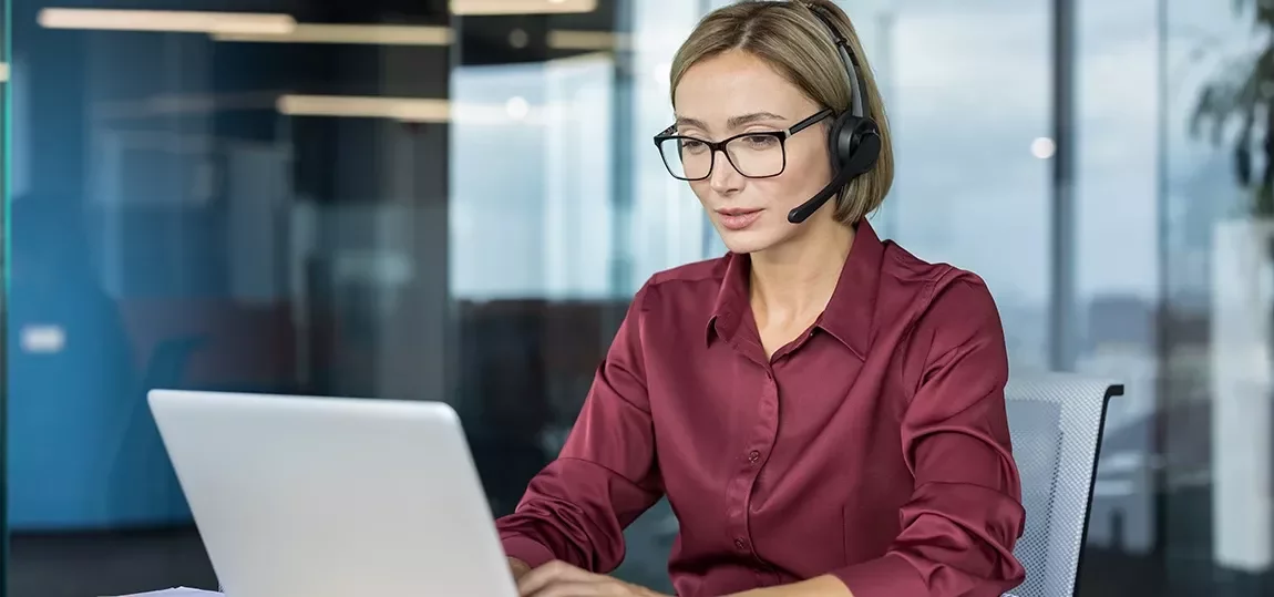 Femme souriante avec un casque micro ou échangeant de façon dynamique devant un écran.