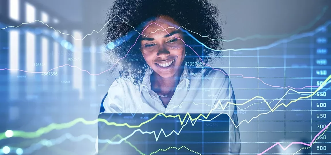 Femme souriant devant un ordinateur qui projette des courbes et graphiques