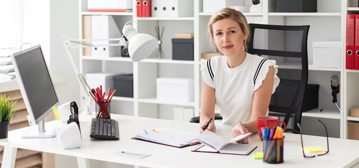Femme devant son bureau de travail avec ordinateur et classeur devant elle