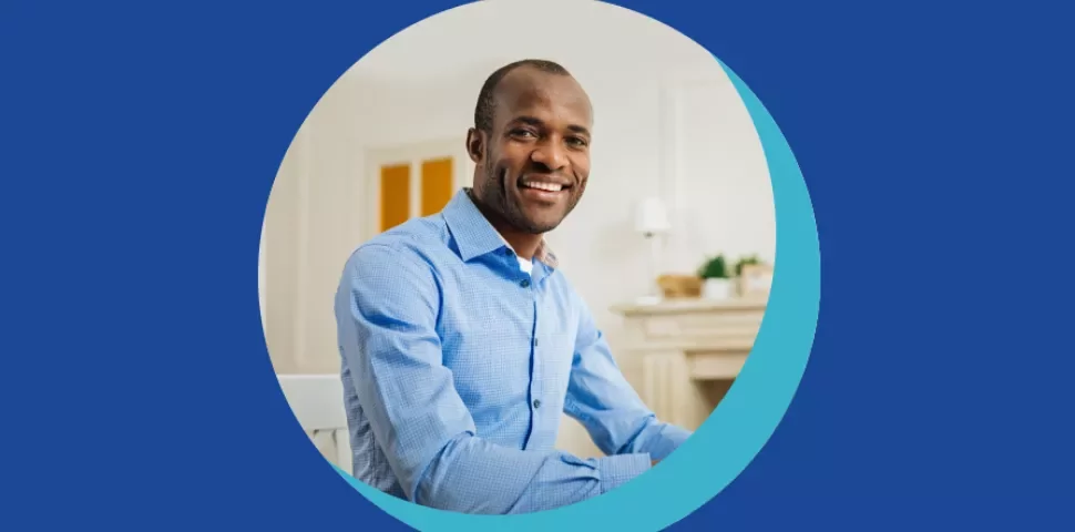 Personne souriante en chemise bleue, assise à une table.
