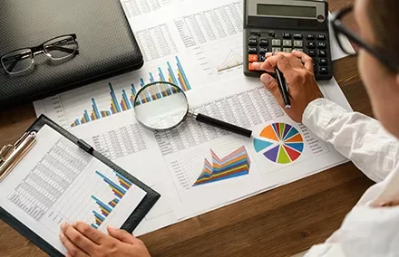 Travail sur des graphiques et calculs financiers sur un bureau en bois.