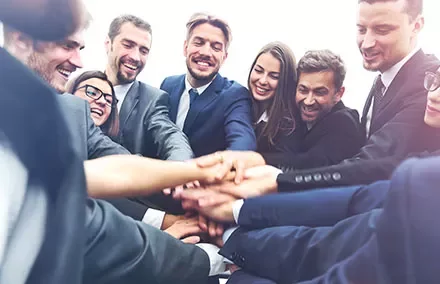 Groupe de collègues souriants se rejoignant les mains.