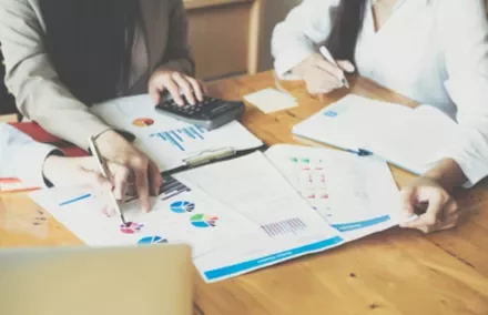 Réunion de travail avec documents et calculatrice.
