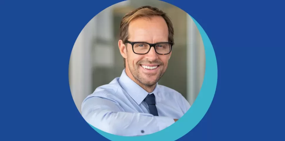 Personne souriante portant des lunettes et une chemise bleue.