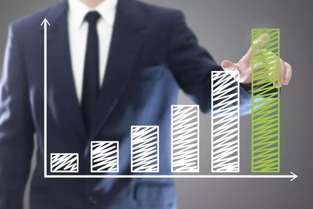 Personne en costume devant un graphique à barres en croissance.