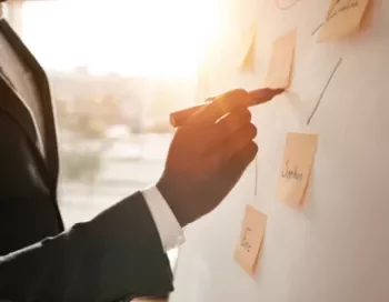 Personne écrivant sur un tableau avec des post-it.