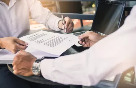 Deux personnes signent un document sur une table.