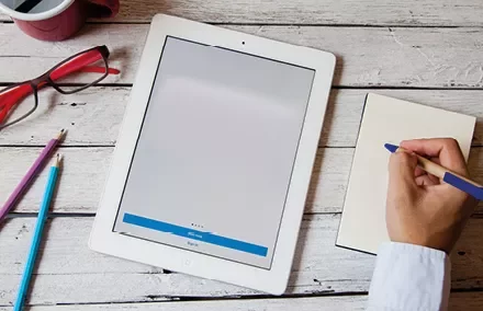 Tablette et bloc-notes sur une table en bois.