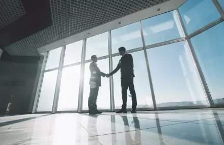 Deux personnes se serrant la main dans un bureau lumineux.