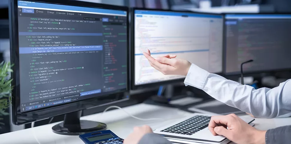 Personnes travaillant sur des codes sur des ordinateurs à plusieurs écrans.